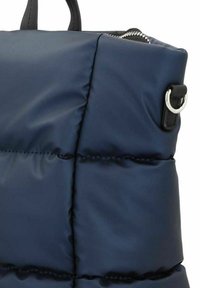Borsa puffa blu navy con texture trapuntata, caratterizzata da dettagli neri, una zip argentata e un anello metallico circolare sul lato.