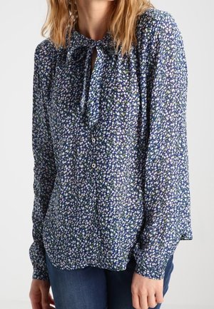 Blusa azul con un estampado floral en púrpura y verde, con escote fruncido y lazo, mangas largas y cierre frontal de botones.