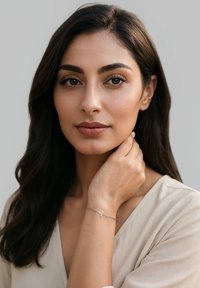 Bracciale d'argento con un ciondolo a croce su un polso, caratterizzato da una delicata catena. Lo sfondo è di un colore tenue, che mette in risalto i dettagli del bracciale.