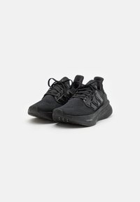 Baskets de sport noires avec un dessus en tricot texturé, des lacets plats et une semelle rembourrée avec des détails de traction fins au fond.