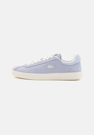 Jasnofioletowy zamszowy sneaker z białymi sznurowadłami, białą podeszwą i małym wyhaftowanym logo po boku.