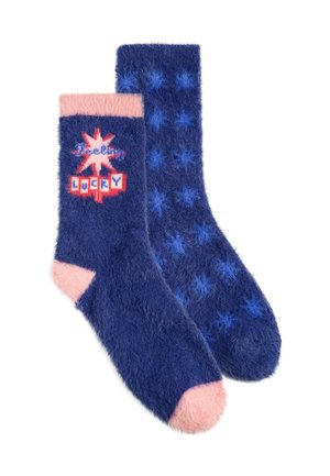 Paar flauschige blaue Socken mit pinken Zehen und Bündchen, ein Socken zeigt Sternenmuster, der andere hat einen roten Stern und den Text "lucky."