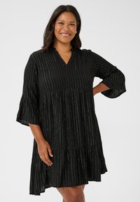 Vestido negro con rayas verticales plateadas, diseño en capas, escote en V y mangas de tres cuartos acampanadas, hecho de una tela ligera.