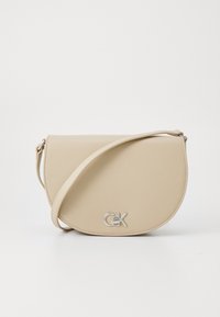 Borsa a tracolla beige con pattina arrotondata, caratterizzata da un logo argentato e una tracolla regolabile. Texture liscia. Design minimalista.