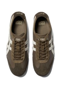 Sneakers z brązowego zamszu i siateczki, z białymi paskami i płaskimi sznurówkami. Okrągły czubek, wyściółka amortyzująca oraz gumowa podeszwa zapewniająca przyczepność.