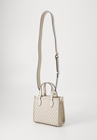 Kleine beige handtas met geweven textuur, twee handvatten en een lange verstelbare schouderriem. Voorzien van goudkleurige hardware en een gestructureerde vorm.