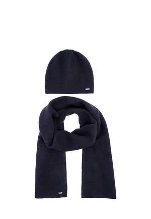 Dark blue knitted hat and matching scarf with small metal brand tags on a white background.
