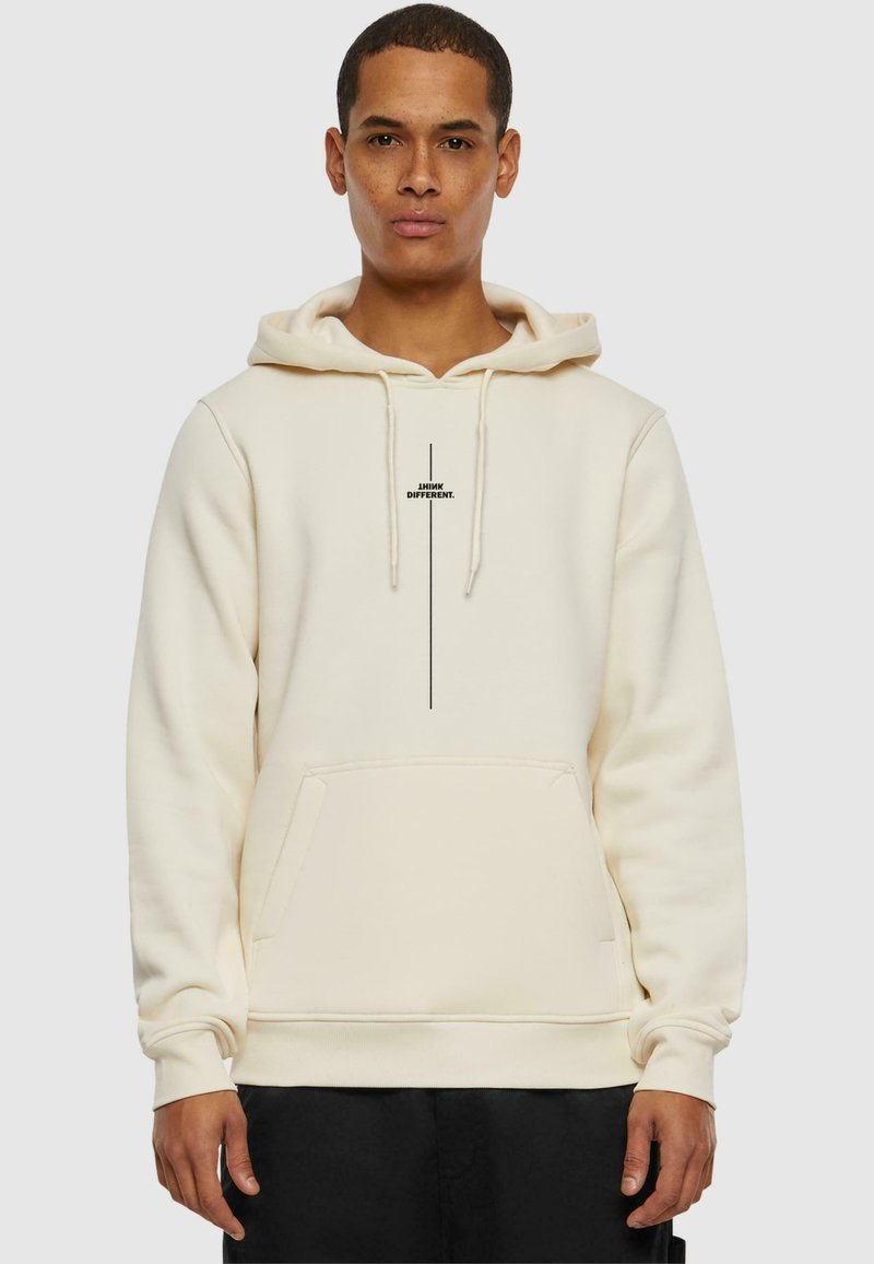 Hoodie crème avec une poche avant, capuche réglable à cordelette, et impression de logo noire au centre. Tissu doux et texturé.