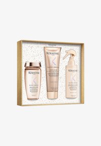 Set regalo Kérastase Gloss Absolu che include tre prodotti in confezione metallica rosa e bianca, presentati in una scatola con macchie dorate.