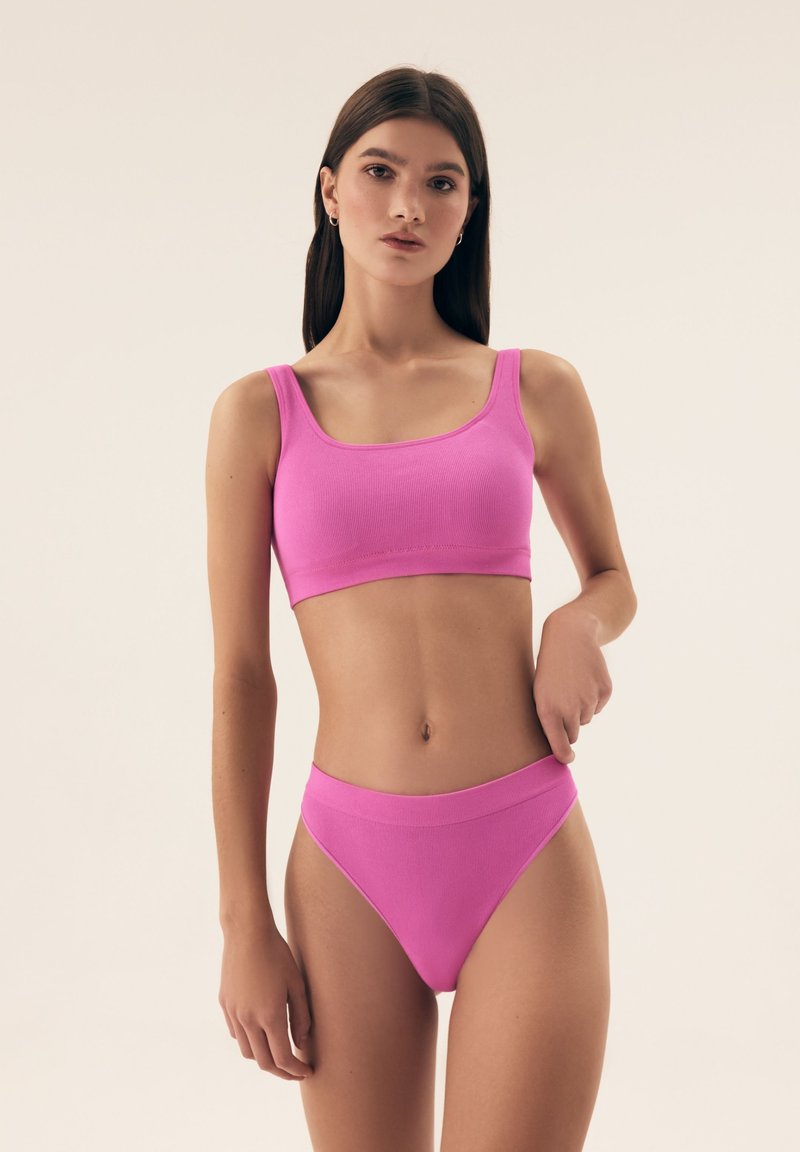 Różowy prążkowany crop top i wysokiej talii majtki bikini, oba z gładką fakturą i szerokimi ramiączkami dla wygody.
