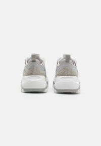 Grå og hvite sneakers med strukturert overdel, avrundet form, trekkflik på hælen og mønstret såle for godt grep.