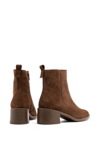 Brązowe zamszowe botki za kostkę na szerokim obcasie, z boku z zamkiem błyskawicznym i pętelką na pięcie. Gładka tekstura i czysta sylwetka.