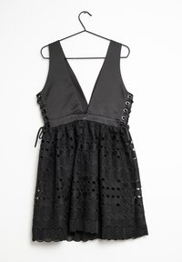 Robe noire avec un décolleté en V profond, dotée d'un corsage structuré et d'une jupe évasée en dentelle hexagonale texturée, accentuée par des côtés à lacets.