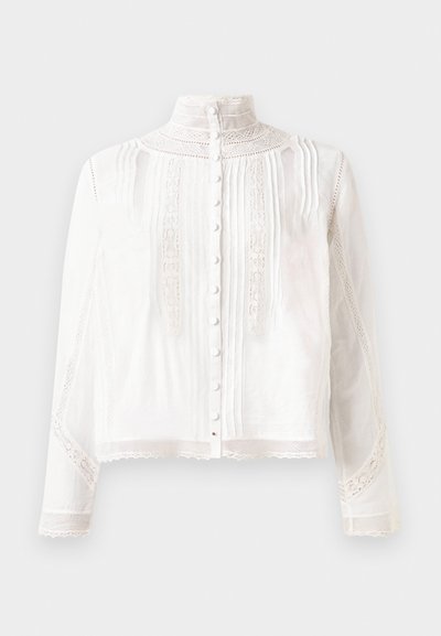 Blusa blanca con cuello alto, mangas largas, plisados verticales, acentos de encaje y cierre de botones en la parte delantera. Tejido ligero con textura semitranslúcida.
