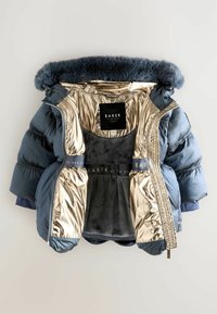 Blå puffjacka med pälsdetalj, guldinsida och grå mjuk insida. Har ribbade muddar och dragkedjestängning. Etikett synlig inuti.