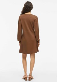 Robe longue à manches longues marron avec un large décolleté, des détails de manches plissées et une coupe décontractée. Se termine au-dessus des genoux; texture lisse.