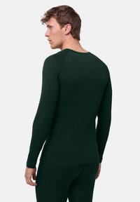 Top met lange mouwen in donker groen, gemaakt van zacht materiaal met een aansluitend ontwerp. Voorzien van een ronde halslijn en smalle manchetten.