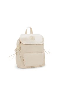 Beige Nylon-Rucksack mit umklappbarem Deckel, Reißverschlusstasche auf der Vorderseite, verstellbaren Kordeln und einem dekorativen Schlüsselanhänger.