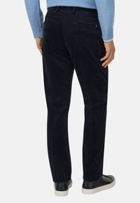 Navy spodnie z korduroju o prostym kroju nogawki, teksturowany materiał, tylne kieszenie i minimalistyczny design, w połączeniu z czarnymi trampkami.