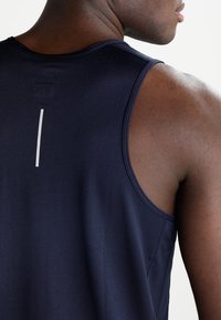 Débardeur athlétique bleu marine avec texture en maille, design sans manches et détail vertical réfléchissant dans le dos.