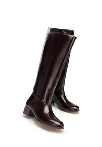 Bordowe, skórzane kozaki sięgające do kolan, o gładkiej fakturze, niewielkim obcasie i zaokrąglonym nosku. Z przodu posiadają podwójny mankiet.