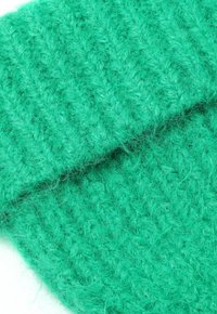 Tessuto lavorato a maglia verde con un motivo testurizzato, caratterizzato da un aspetto morbido e soffice. La trama è densa e visibile, creando un aspetto accogliente.