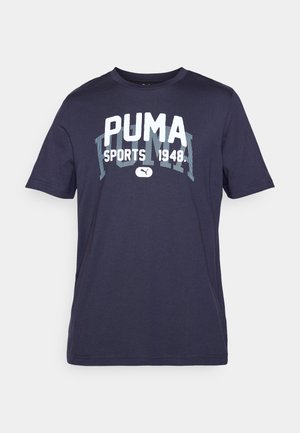 Tumši zilā krāsa kokvilnas T-kreklā ar īsām piedurknēm un apaļu izgriezumu. Priekšpusē ir liela balta grafika "PUMA SPORTS 1948".