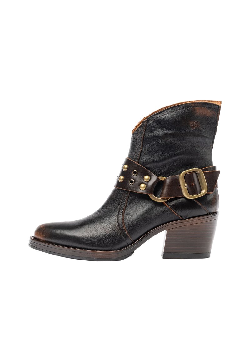 Stivale alla caviglia in pelle nera con una cinghia in pelle marrone che presenta un hardware dorato e una fibbia quadrata. Tacco in legno elevato, design a punta.