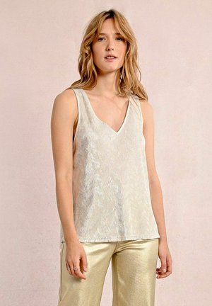 Top senza maniche di un oro metallico con scollatura a V, caratterizzato da una lucentezza testurizzata e un orlo dritto. Abbinato a pantaloni ampi in oro lucido.