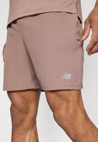 Lys brunid IDR shorts med en glatt tekstur, med et brodert hvitt logo på kanten. Designet for komfort og bevegelighet.