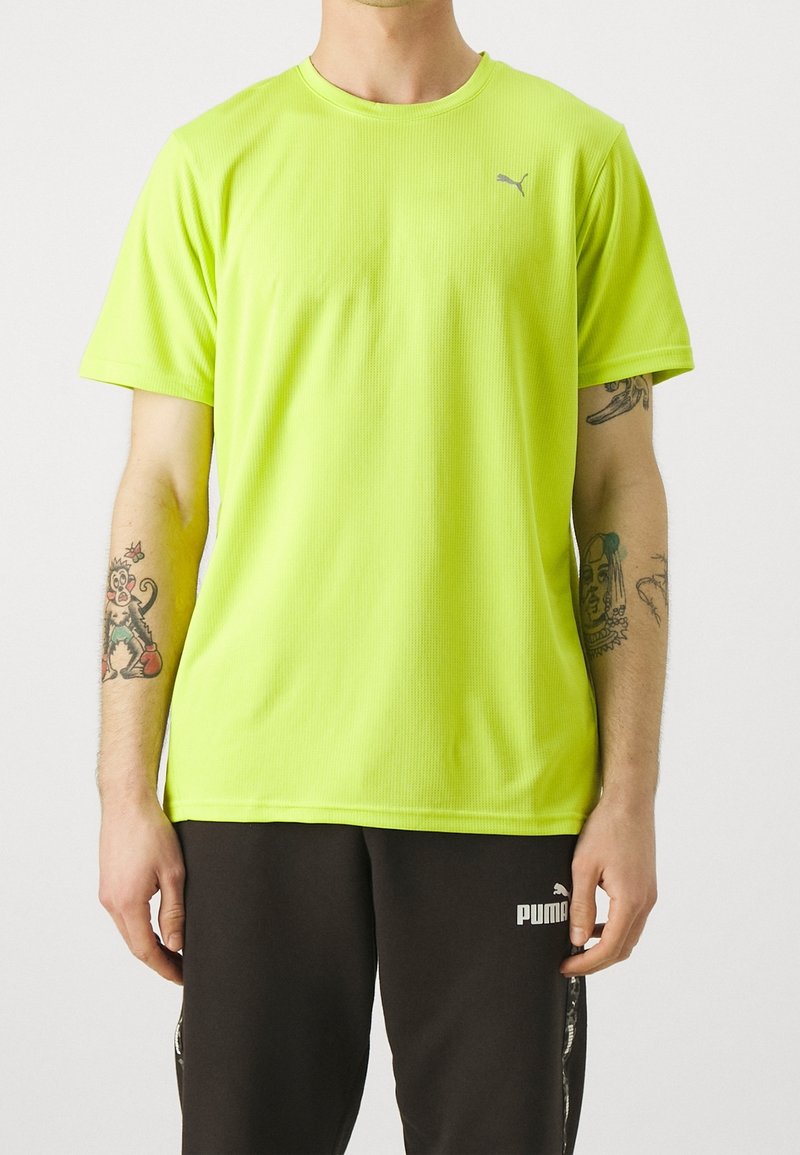 Camiseta deportiva amarilla neón de manga corta, con textura acanalada y un pequeño logo gris de Puma en el pecho. Se lleva con pantalones de chándal oscuros.