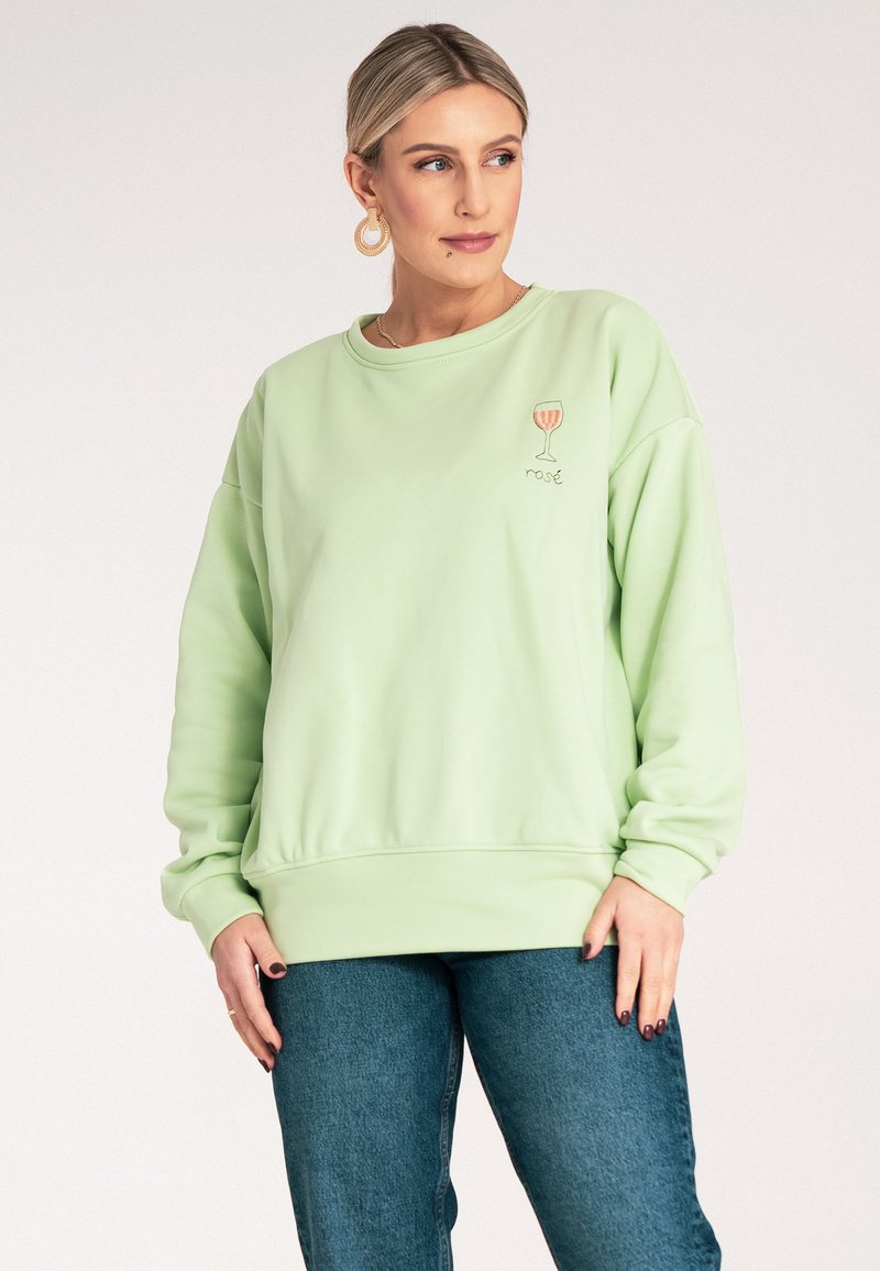 Miętowy sweter z okrągłym dekoltem, ribbowymi mankietami i dołem. Posiada haftowany kieliszek wina i napis "rosé" na klatce piersiowej.