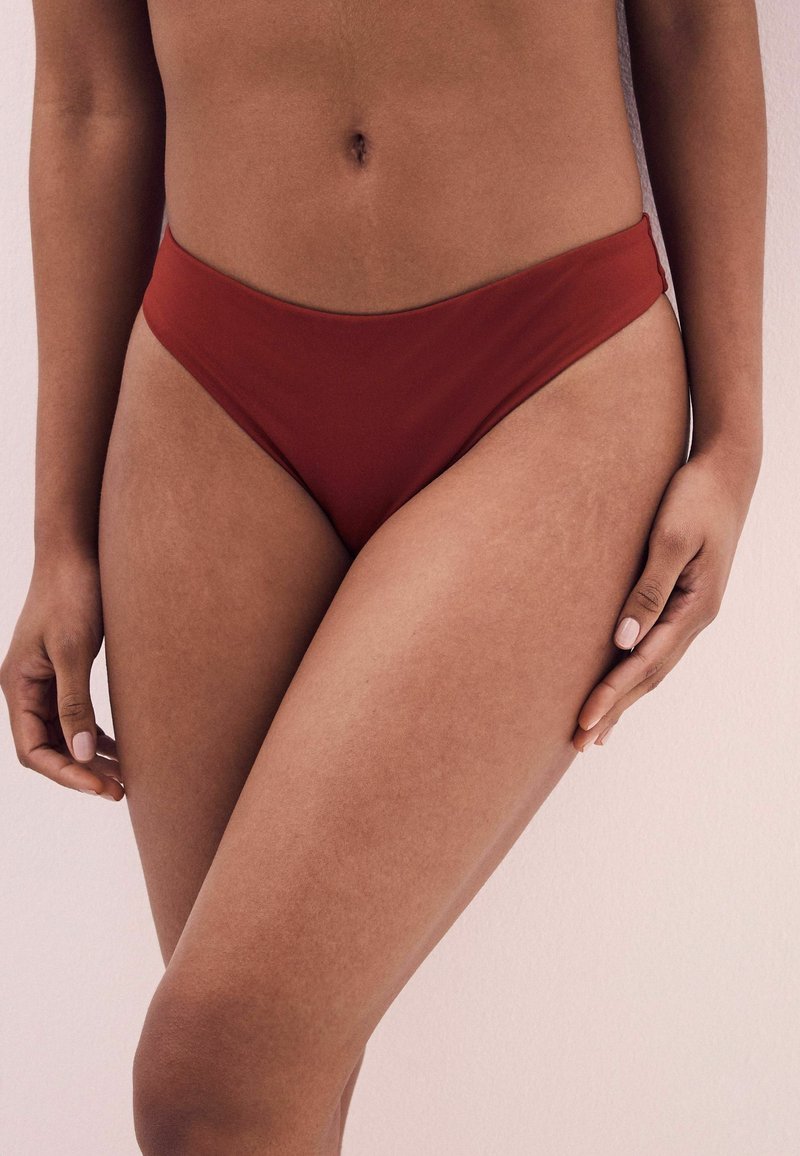 Röd bikiniunderdel med högskuren, minimalistisk design. Slät textur och elastiskt band runt midjan, utan synlig hårdvara eller mönster.