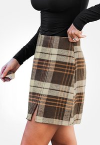 Gonna mini a quadri in tonalità marrone, beige e arancione, realizzata in un tessuto testurizzato. Presenta uno spacco laterale e un design a vita aderente.