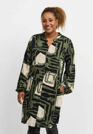 Long-sleeve shirt dress in black, olive green, and cream with an abstract square pattern. Features a v-neckline and side pockets.
