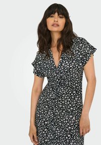 Zwarte bloemenjurk met een V-hals, korte fladdermouwen en een aansluitende taille. Kenmerkt zich door kleine witte en roze bloemenpatronen.