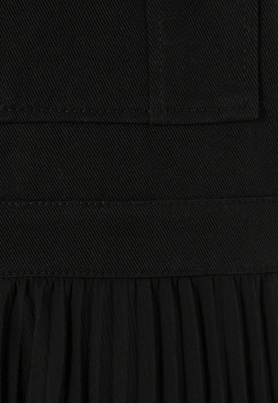 Robe noire plissée en tissu texturé. Présente une partie supérieure lisse et une jupe fluide et froncée. Aucun matériel visible ni motifs.