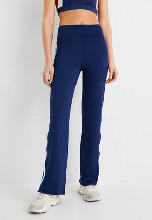 Marineblauwe sportbroek met een getailleerd ontwerp, hoge taille en uitlopende pijpen. Voorzien van witte zijkanten en een gladde, rekbare stof.