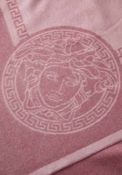 Couverture en laine rose arborant un design Méduse et un motif grec, avec une texture douce et des nuances contrastées dans le tissu.