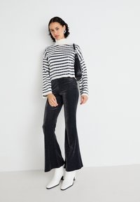 Striped cropped sweater in cream and navy, paired with black glitter flared pants. White ankle boots with black soles, minimalist black handbag.