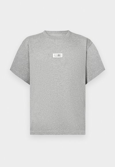 Siva majica s kratkimi rokavi iz mehke bombažne tkanine. Spredaj ima pravokotni etiketo s črnim besedilom in minimalističnim dizajnom.