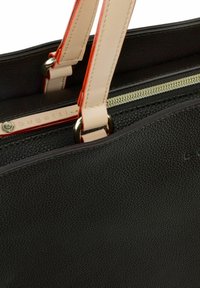 Sac à main en synthétique texturé noir avec des poignées beige clair contrastantes et des accents orange, ainsi qu'une fermeture éclair dorée.