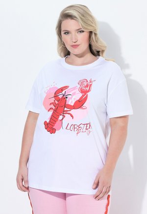 Kobieta o blond włosach, ubrana w białą koszulkę z czerwonym homarem, trzymająca koktajl i napis "Lobster party", w połączeniu z różowymi spodniami z czerwonymi paskami.