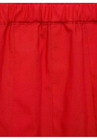 Tejido rojo con una textura suave, que presenta pliegues suaves y una cinturilla elástica. El color es brillante y uniforme en todo el tejido.