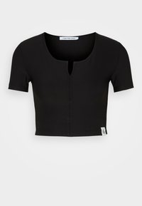 T-shirt cropped noir avec une texture côtelée, des manches courtes, un col rond et un détail de bouton central. Étiquette de marque Calvin Klein Jeans incluse.