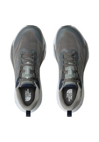 Harmaat urheilukengät, joissa on verkkomaiset yläosat, tekstuuripinnat, tasaiset kengännauhat, pyöreä kärki sekä kontrastiset laivastonsiniset yksityiskohdat sivuilla ja heinällä.