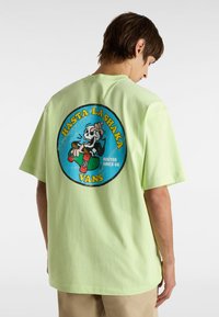 Light green cotton t-shirt featuring a large circular graphic on the back with a skull, skateboard, and text "HASTA LA SHAKA VANS".