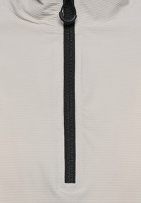 Hellgrauer Pullover mit einem schwarzen Reißverschluss, der aus strukturiertem Stoff gefertigt ist und einen hohen Kragen hat. Kontrastnähte entlang des Reißverschlusses sorgen für zusätzliche Details.