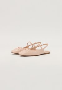 Bottines plates rose clair avec un bout rond, présentant des détails froncés à l'avant et deux accents de bande réglables à la cheville.