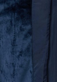 Marineblauwe stof met een zachte, pluche textuur en een glad gedeelte in contrast, met rijke kleuren en zijnaaddetails.
